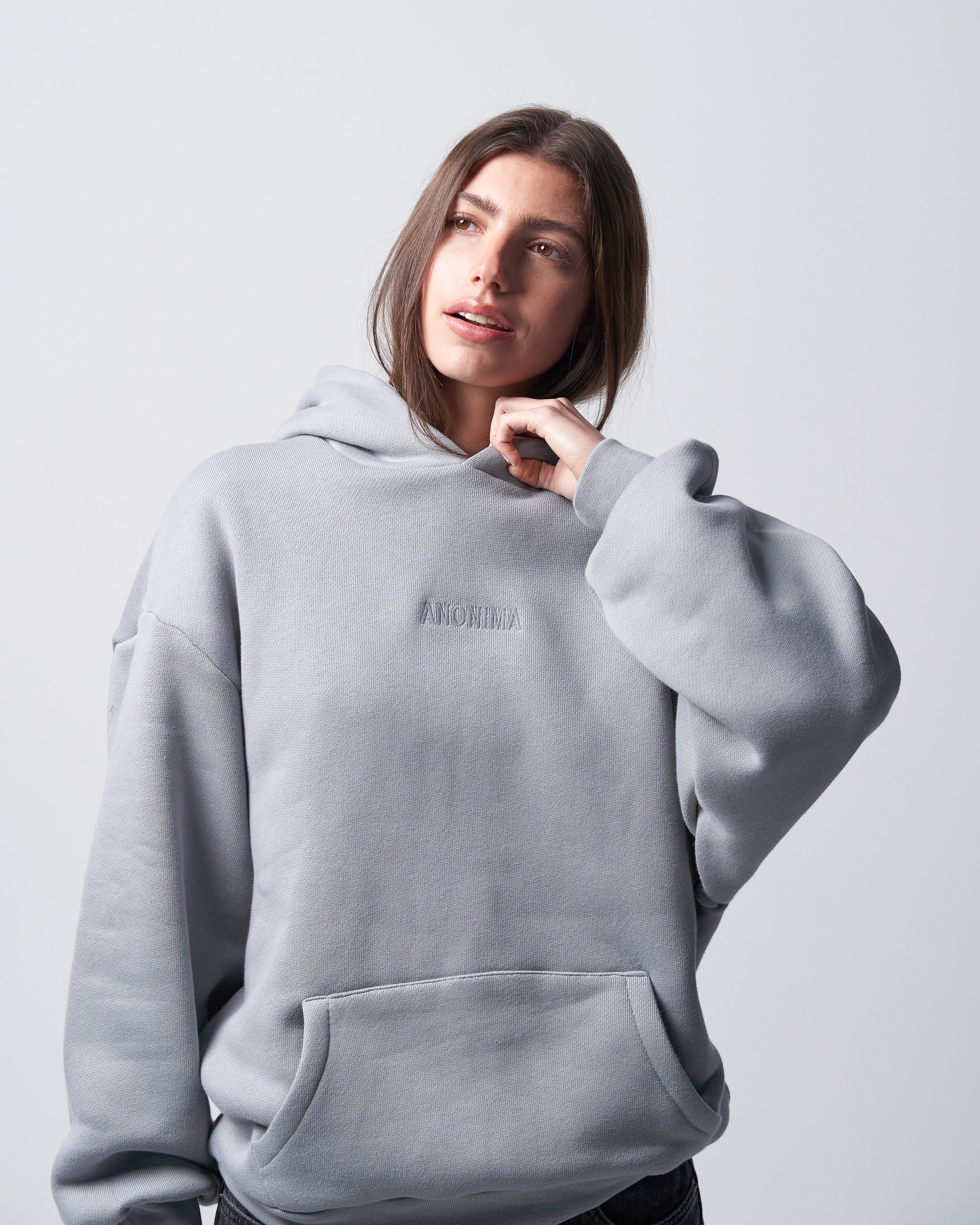 Person wearing a light gray hoodie with a brand logo on a plain background
