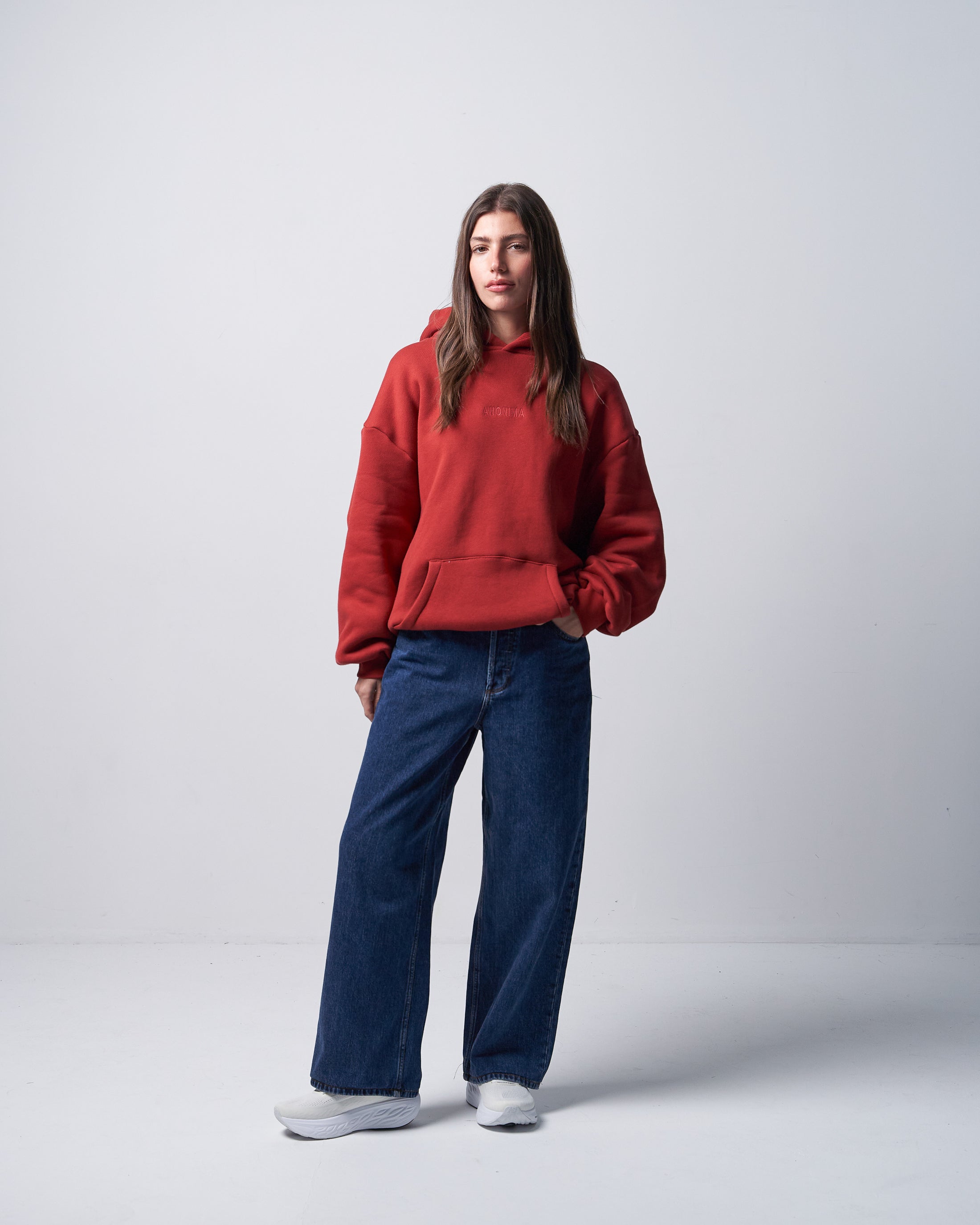 Person wearing a red hoodie and blue jeans on a white background