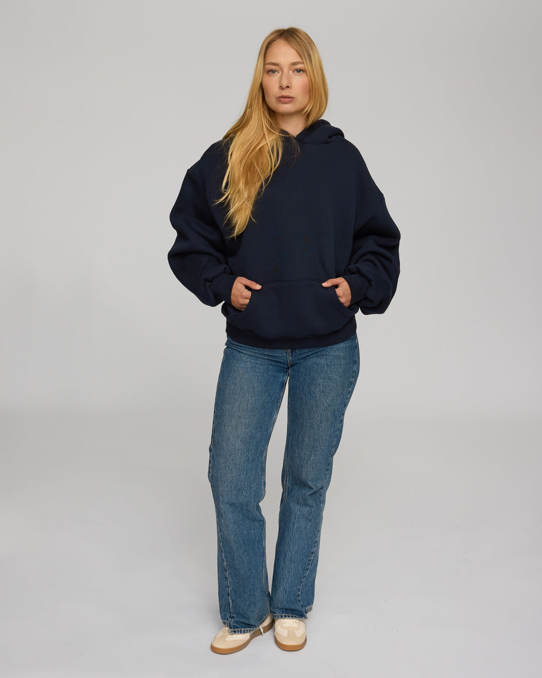 Person wearing a navy hoodie and blue jeans on a plain background