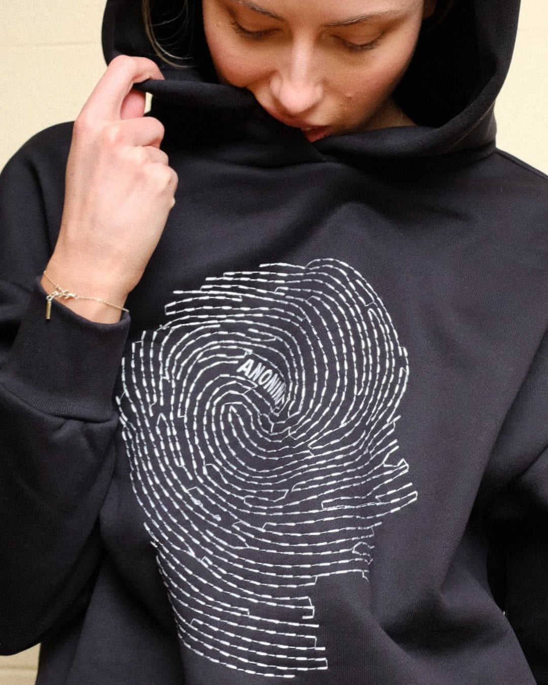 Person wearing a black hoodie with a white graphic design on a beige background