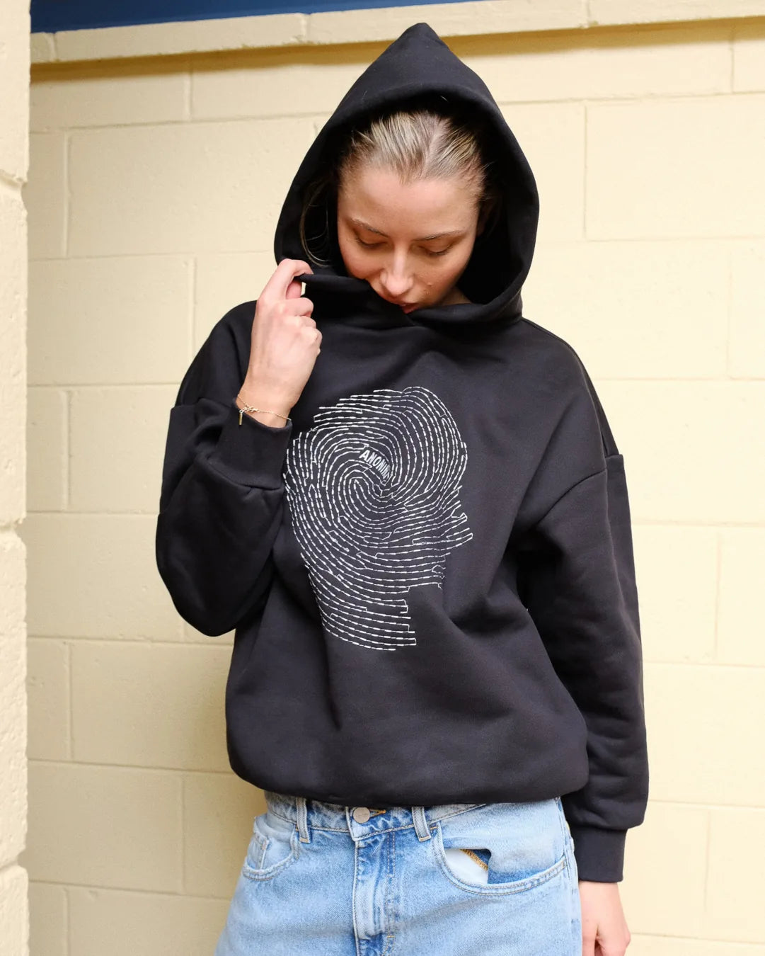 Woman wearing Societa Anonima hoodie in black with fingerprint embroidery on the front