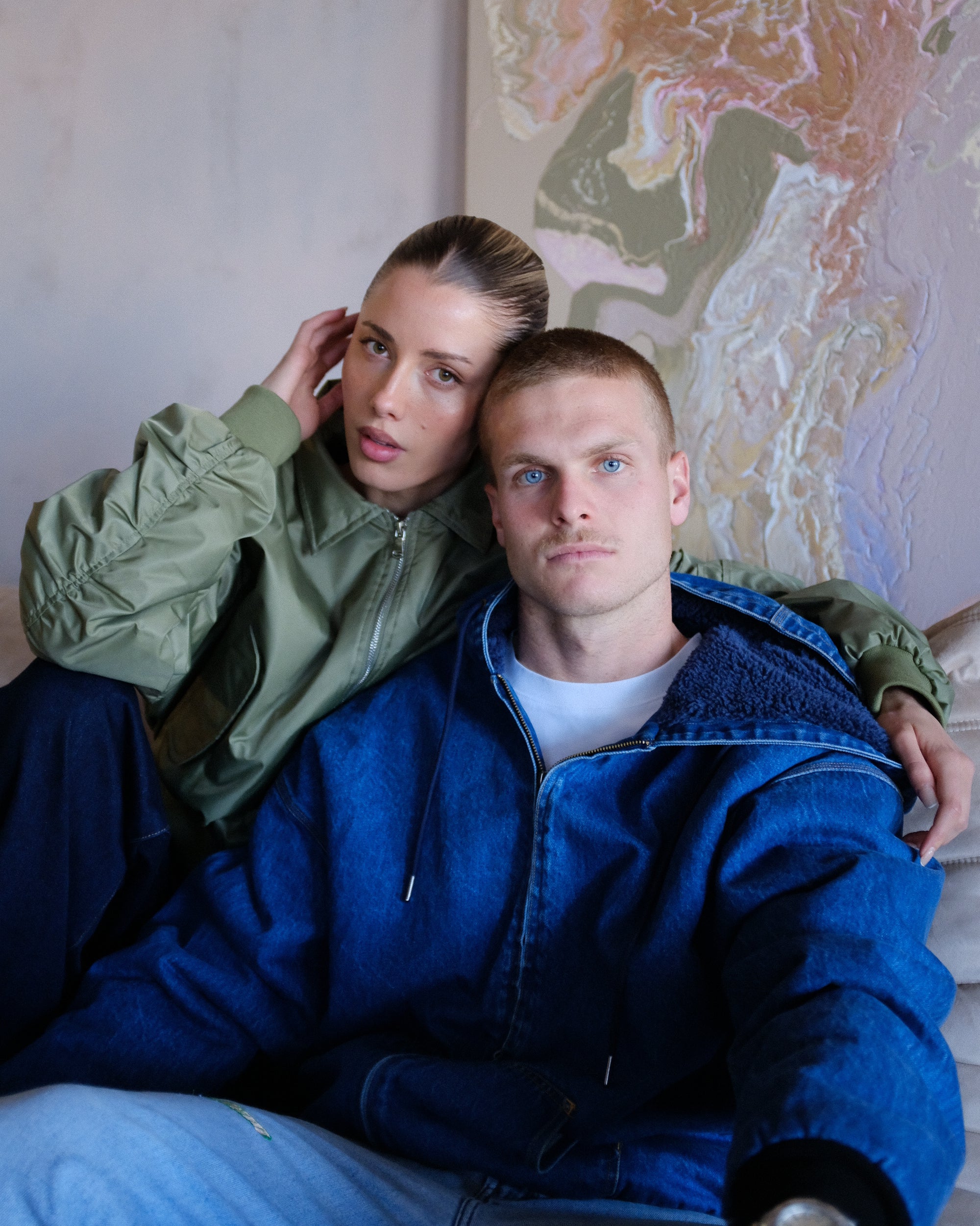 Two people sitting close together with a colorful abstract painting in the background
