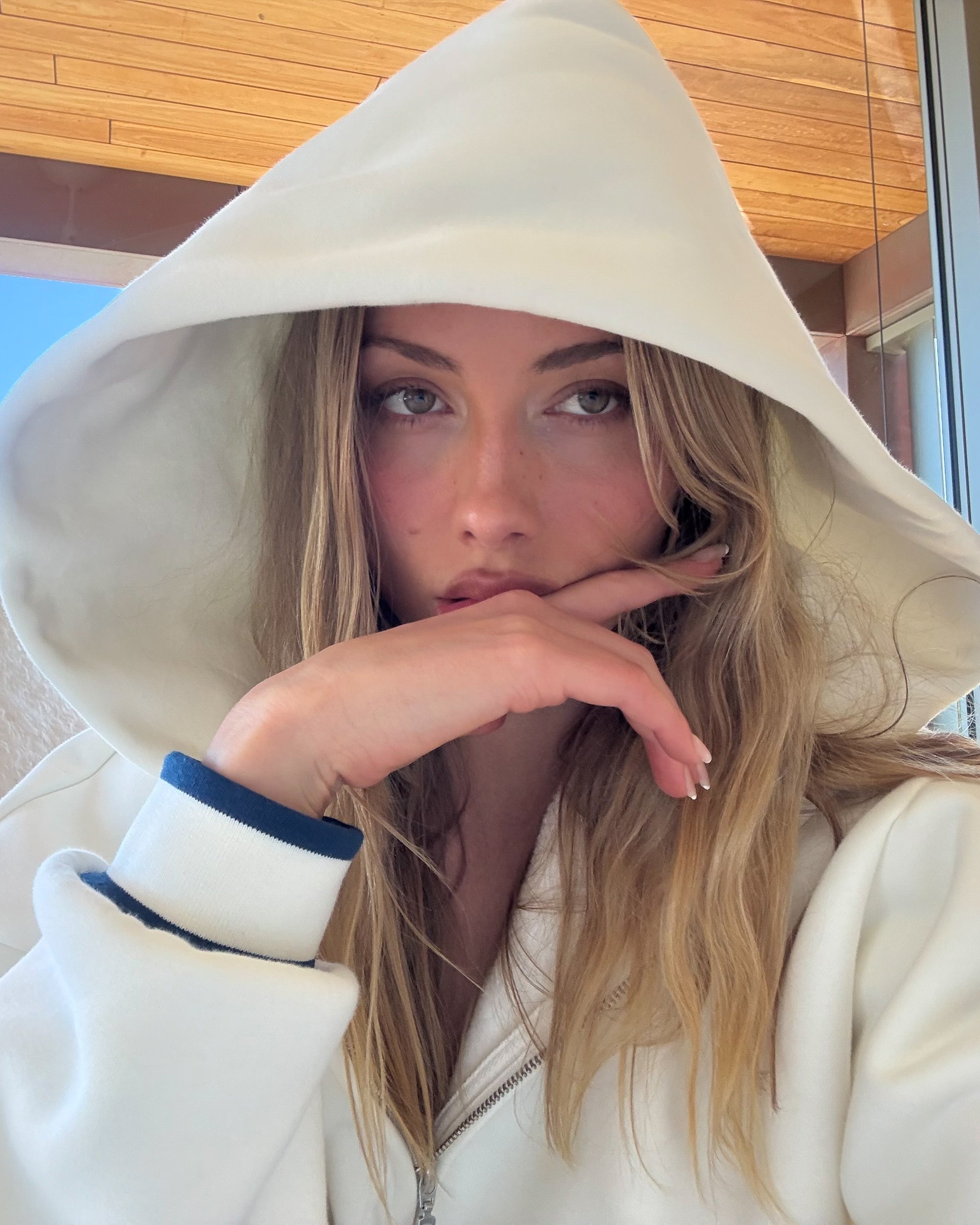 Person wearing a white hoodie with a hood, indoors.