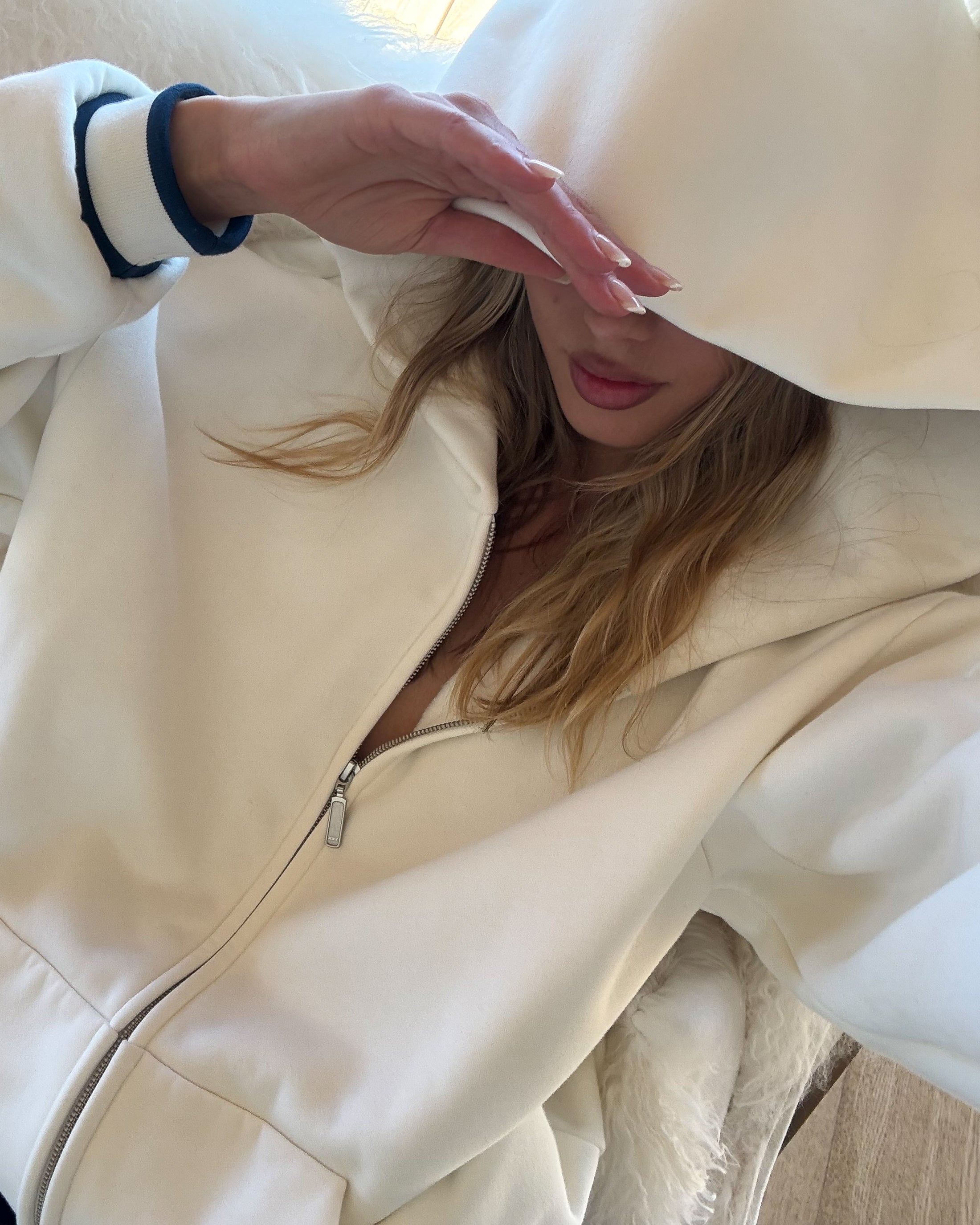 Person wearing a white coat with a hood, partially covering their face.