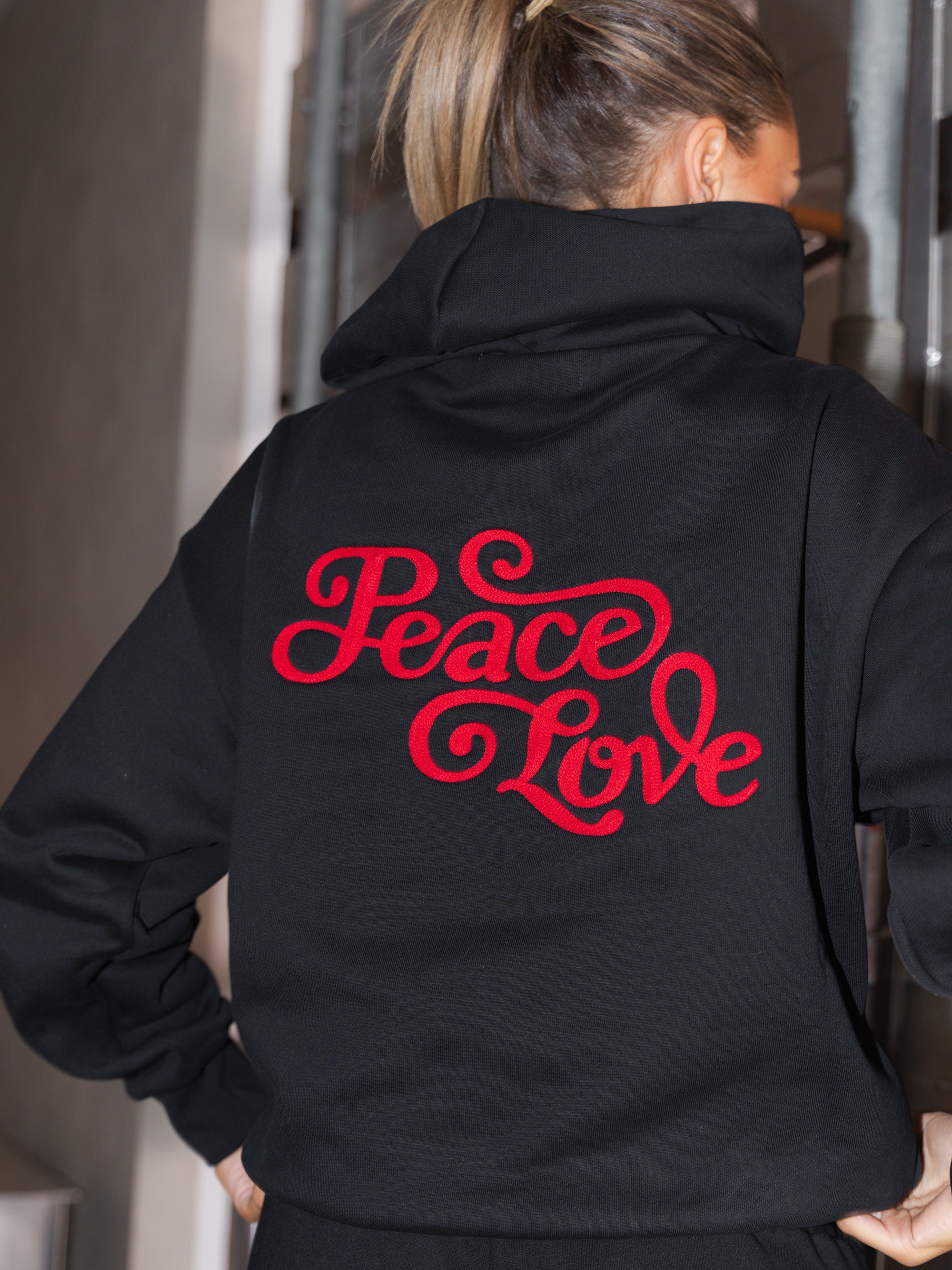 Person wearing a black hoodie with 'Peace Love' in red text on the back.