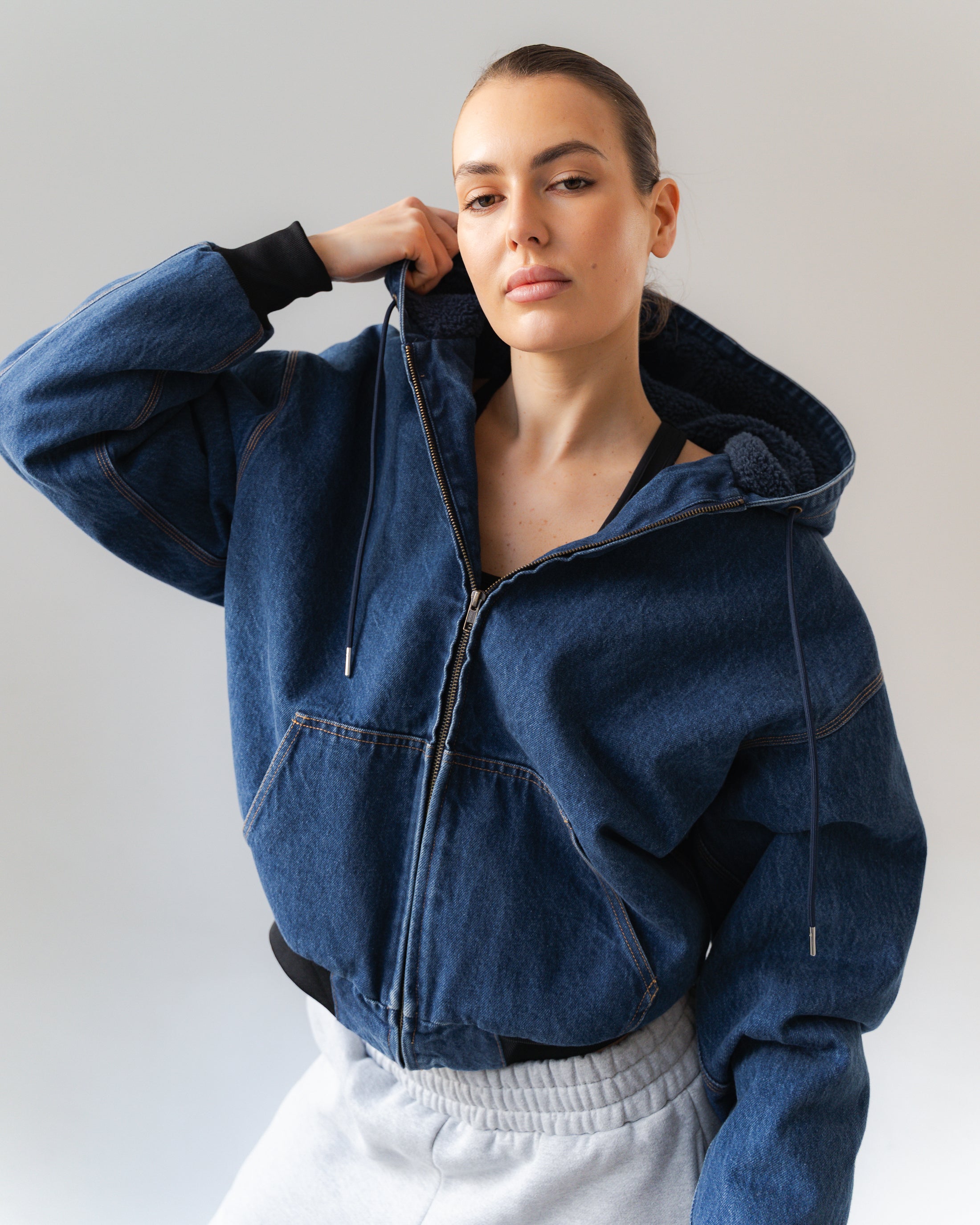 Person wearing a blue denim jacket against a plain background