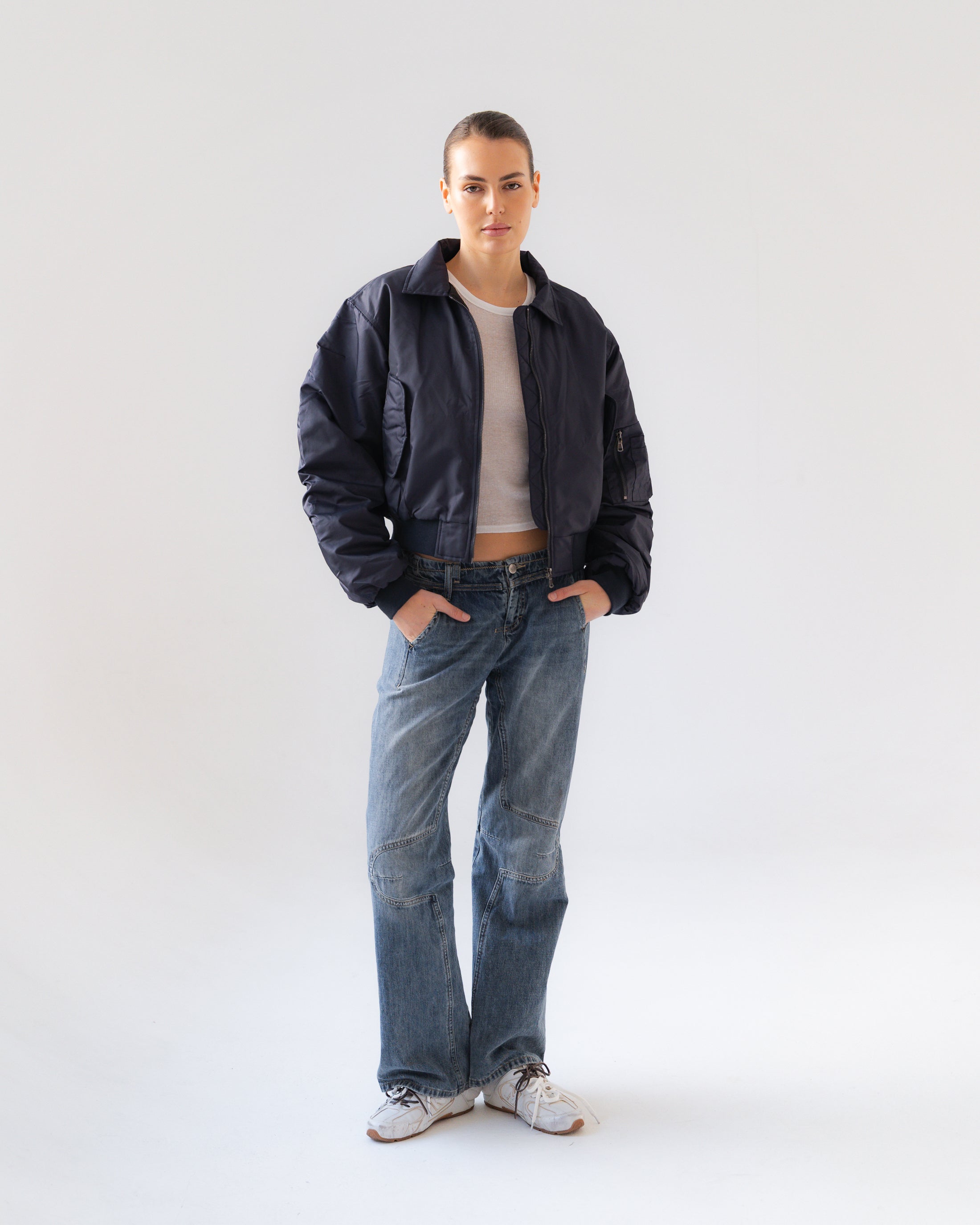 Person wearing a black jacket, white shirt, and blue jeans on a white background