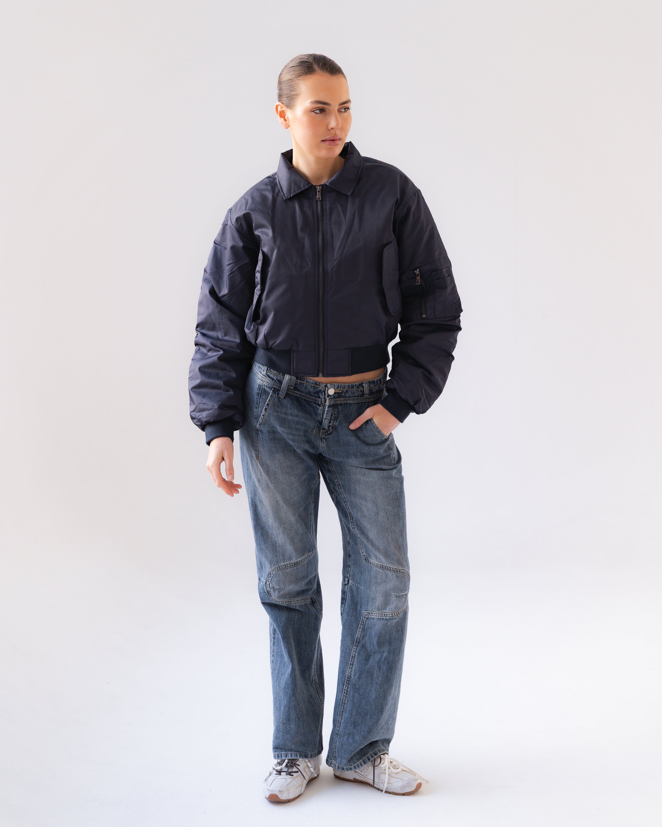 Person wearing a dark jacket and blue jeans on a white background