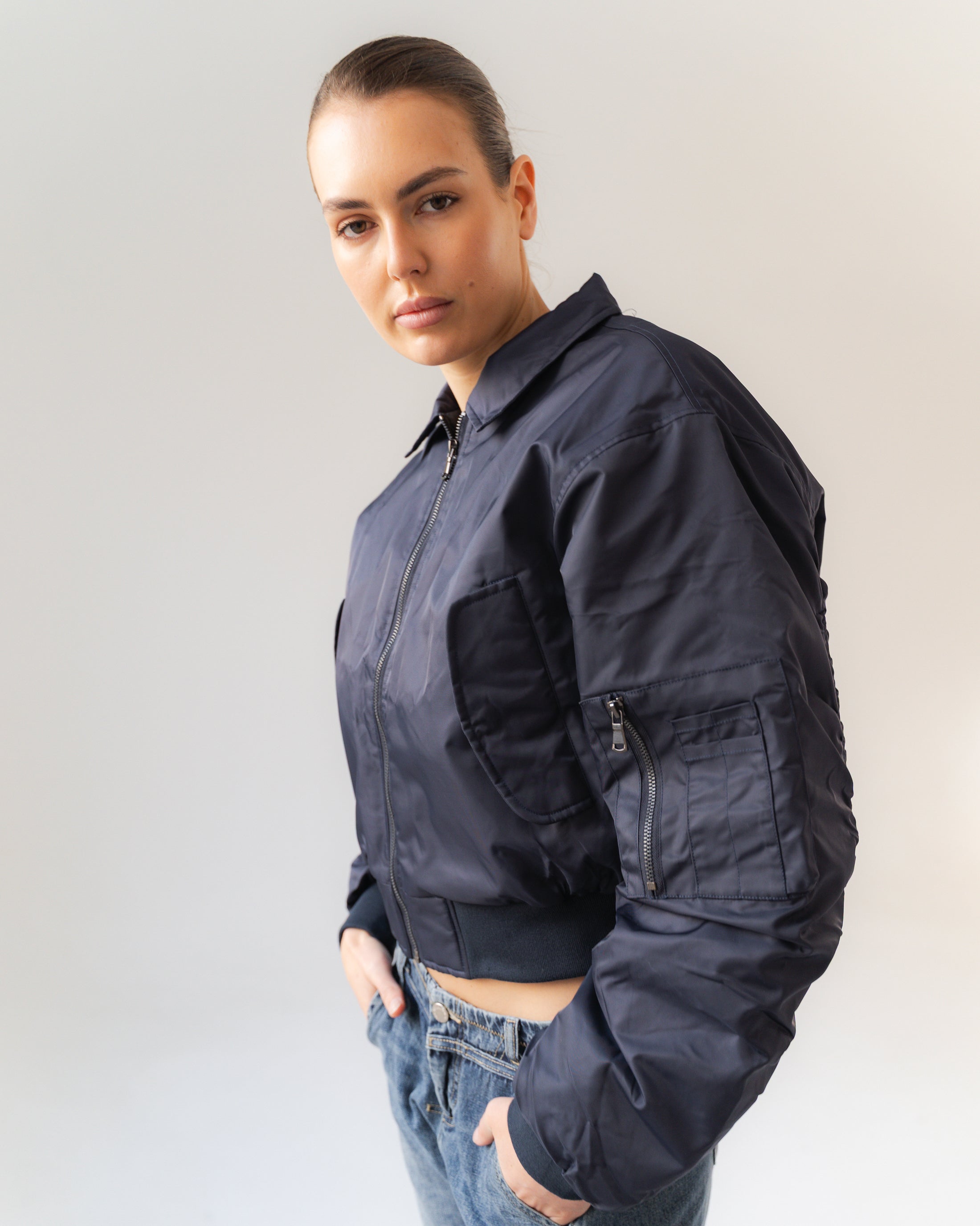 Person wearing a dark blue bomber jacket against a plain background