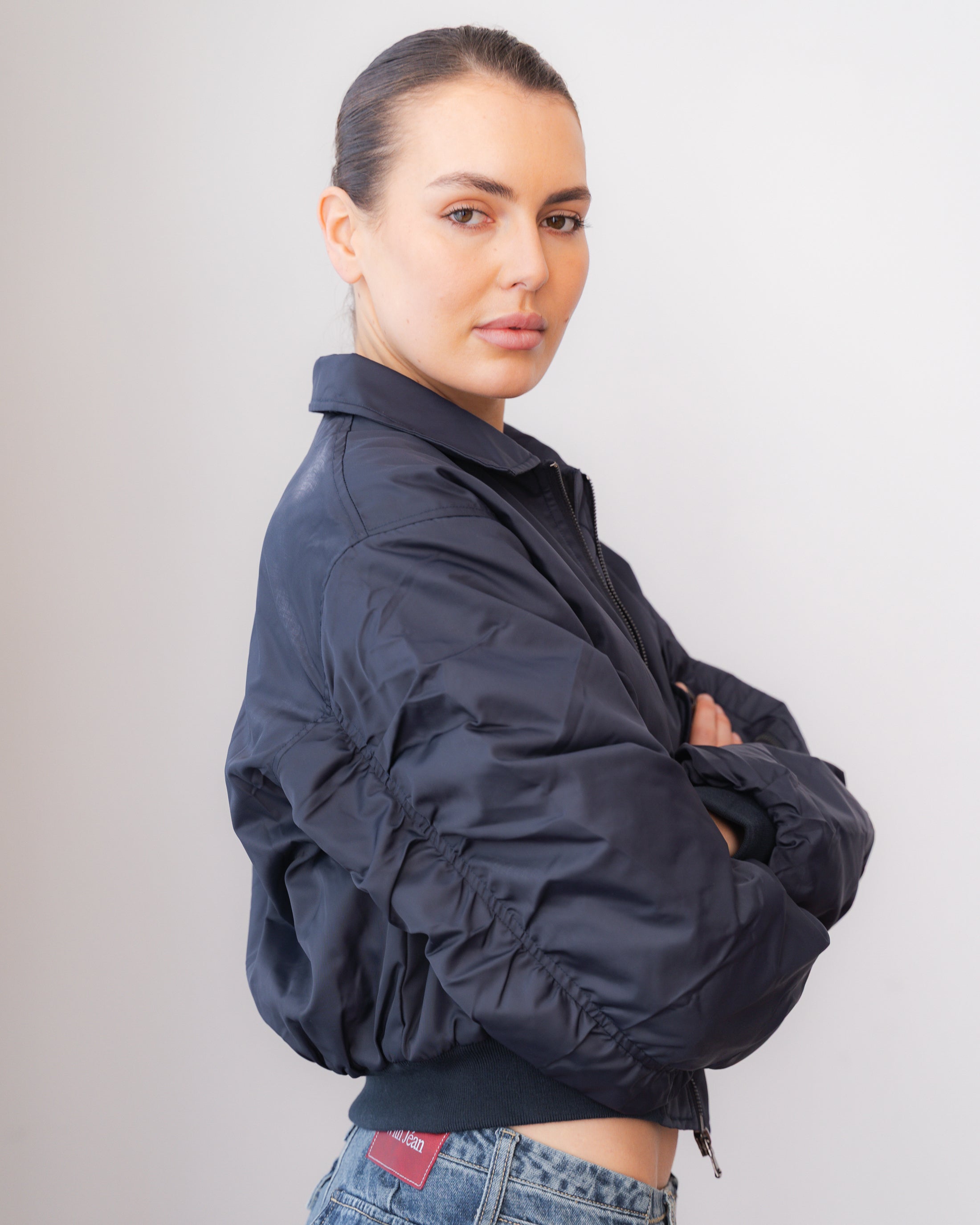 Person wearing a navy blue jacket with a plain background