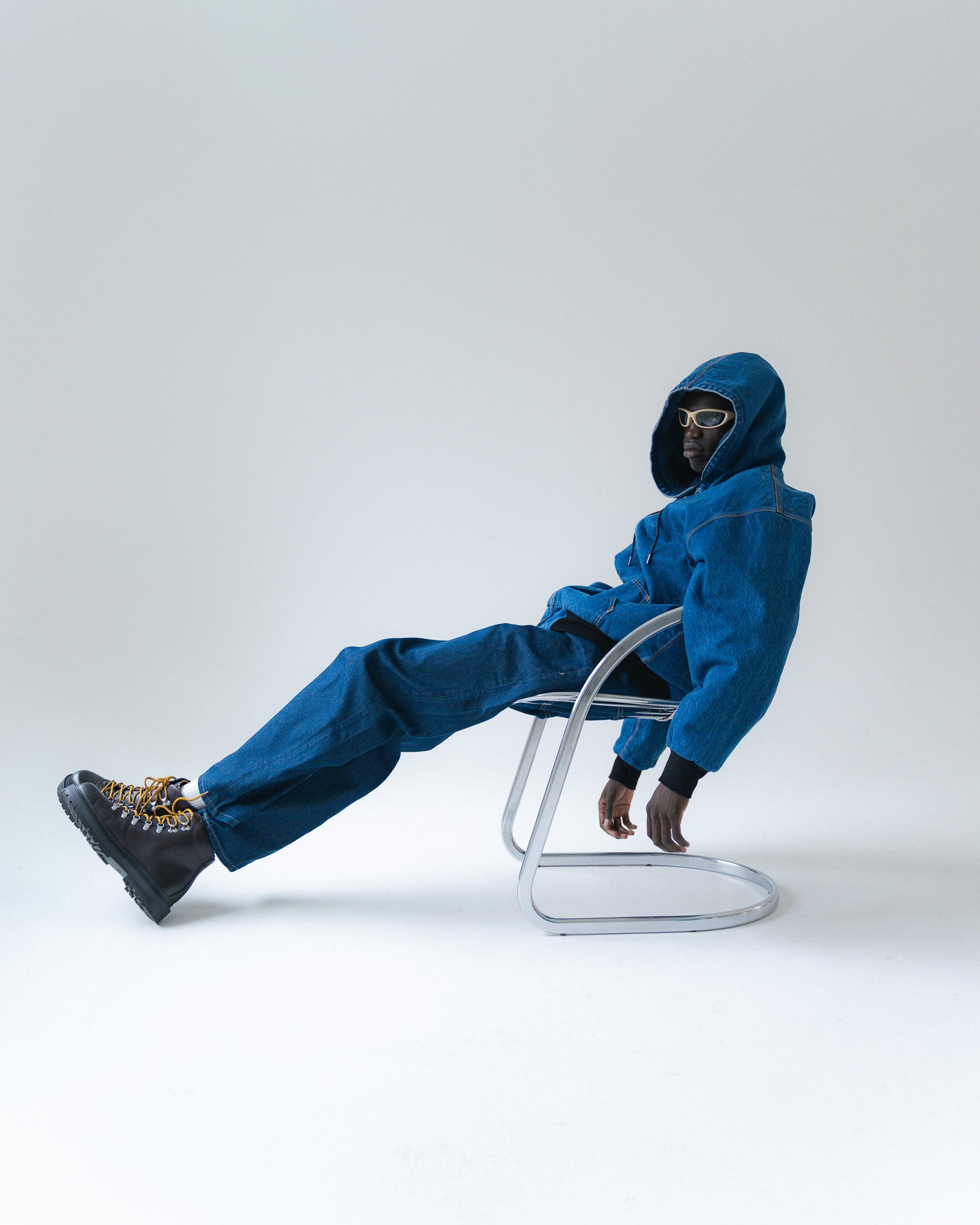 Person wearing a blue outfit sitting on a chair against a white background