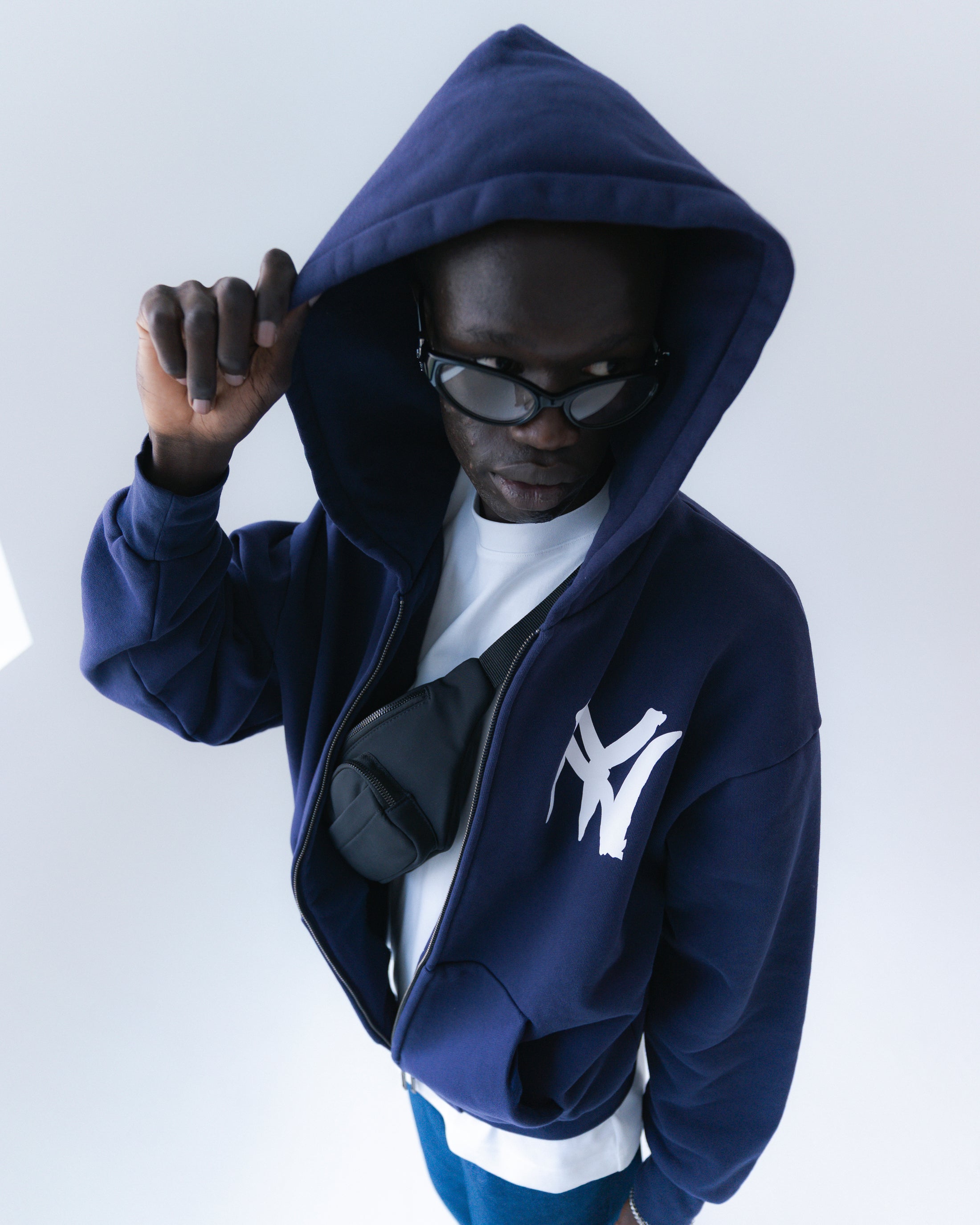Person wearing a navy blue hoodie with a logo on a white background