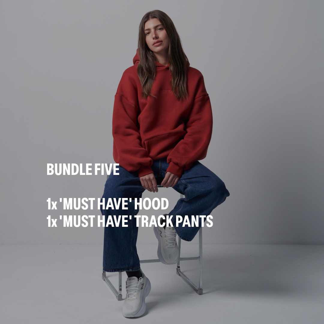 Person wearing a red hoodie and blue jeans sitting on a stool against a plain background